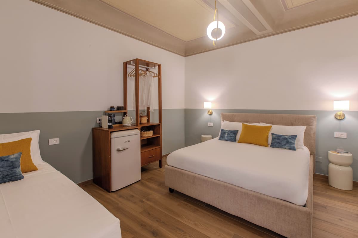 A bedroom with two beds, a dresser, a mirror, bedside lamps, and a ceiling light.