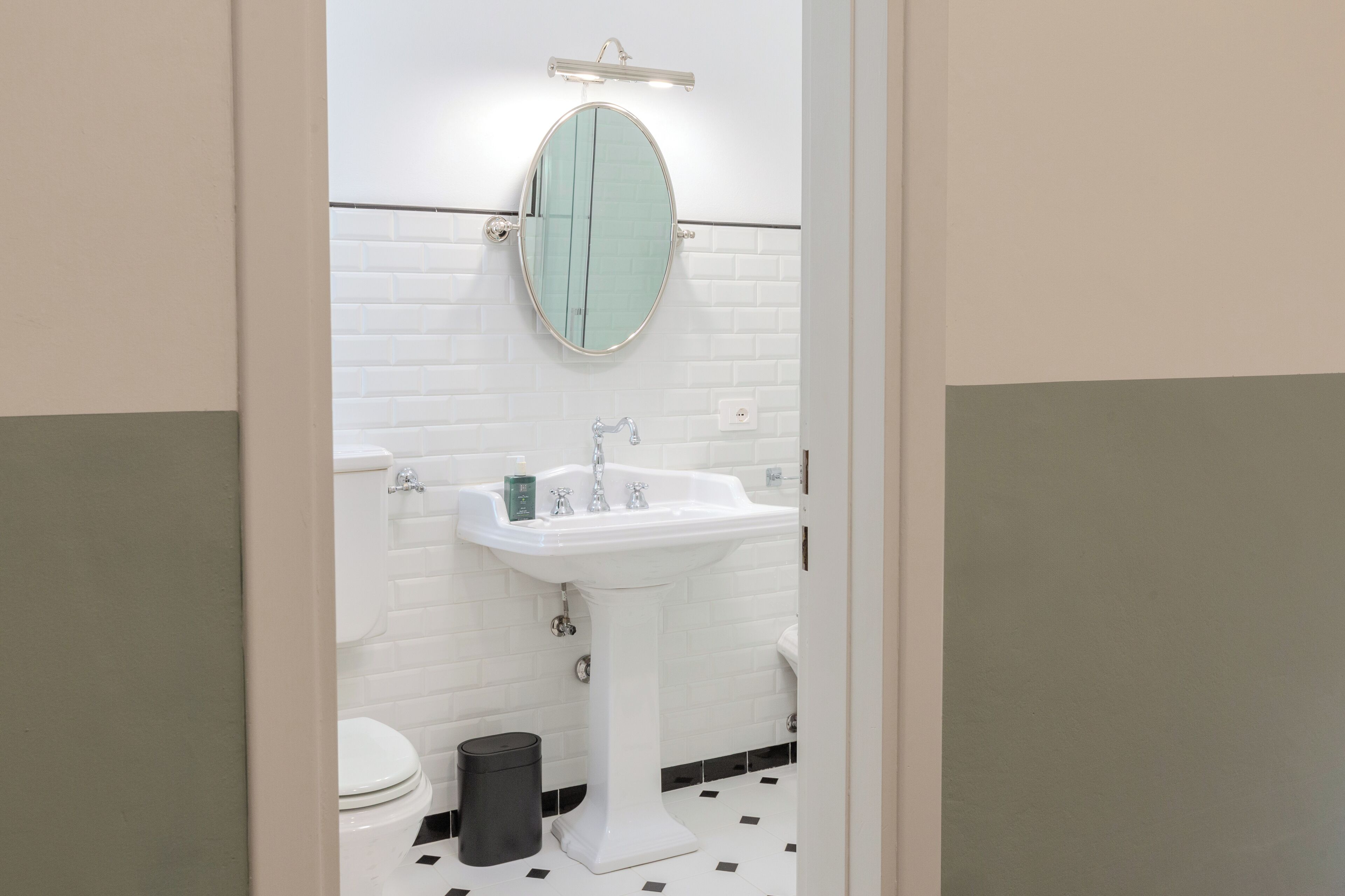 A bathroom with a white sink, a mirror, and a toilet.