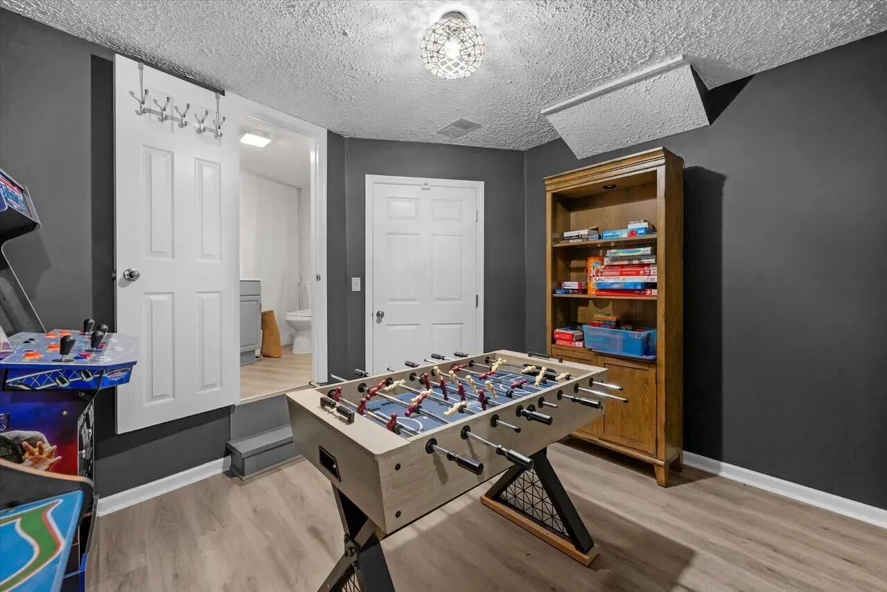Una habitación con mesa de fútbol, estantería y una puerta.