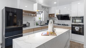 Una cocina moderna con una isla grande, electrodomésticos integrados y encimera de mármol.