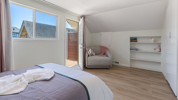 Un dormitorio con cama, una silla, un armario y vistas al exterior.
