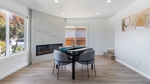 Un comedor moderno con pared de mármol, chimenea y vistas al exterior.