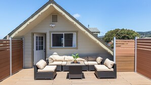 Une terrasse couverte avec un canapé et une table, une porte et une fenêtre.