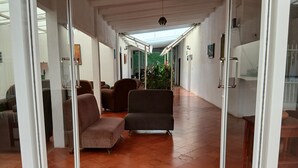 A corridor with a tiled floor, two sofas, and a hanging light fixture. - Managua Inn (Managua)