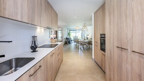 Eine moderne Küche mit Holzschränken, einem Edelstahlspülbecken und einem Essbereich im Hintergrund.