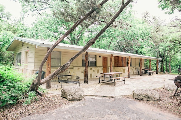 A rustic cabin with a patio, outdoor seating, and a barbecue grill.