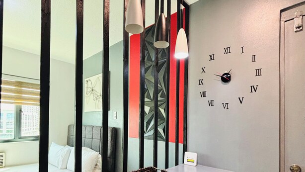 A modern kitchen with a bar area, a clock on the wall, and a view of a bedroom through a partition. - Award-winning Stay in Iloilo (Iloilo)