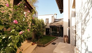 A narrow alleyway with a small garden area, a building with a tiled roof, and a glass door entrance. - Bonaventura House - House near Mount Etna (Unknown)