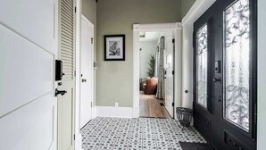 Un couloir doté d’un revêtement de sol à motifs, une porte avec des panneaux de verre dépoli et un tableau encadré accroché au mur.