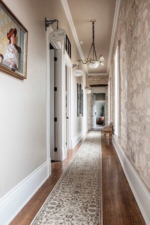 A hallway with a patterned rug, a chandelier, and a door labeled "The Vault".