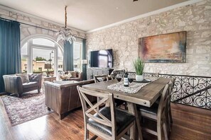 Un coin repas avec une table en bois, des chaises et un téléviseur fixé au mur.