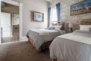 Een slaapkamer met twee bedden, een stenen muur, een schilderij en een raam met gordijnen.