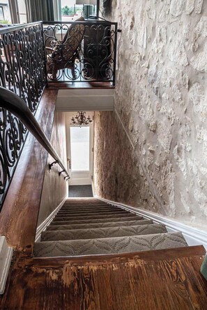 A wooden staircase with a wrought iron railing leading to a door. - The Bank on Main St - Downtown Escape Featuring a Deck w/Main St Views! (Fredericksburg)