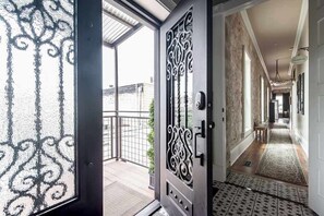 Un couloir doté d’un sol à motifs, d’une porte décorative et donnant sur le balcon ext érieur.