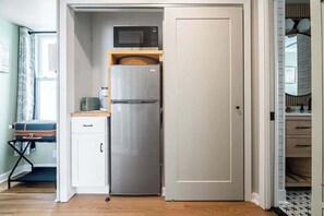 A compact kitchen with a built-in microwave, a stainless steel refrigerator, and a small countertop. - The Bank on Main St - Downtown Escape Featuring a Deck w/Main St Views! (Fredericksburg)