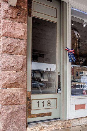 A door with the number 118, a stone wall, and a window with a reflection of buildings. - The Bank on Main St - Downtown Escape Featuring a Deck w/Main St Views! (Fredericksburg)