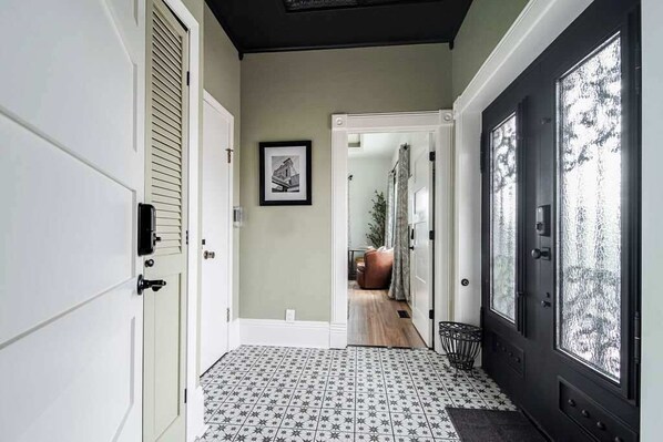 A hallway with patterned flooring, a door with frosted glass panels, and a framed picture on the wall.