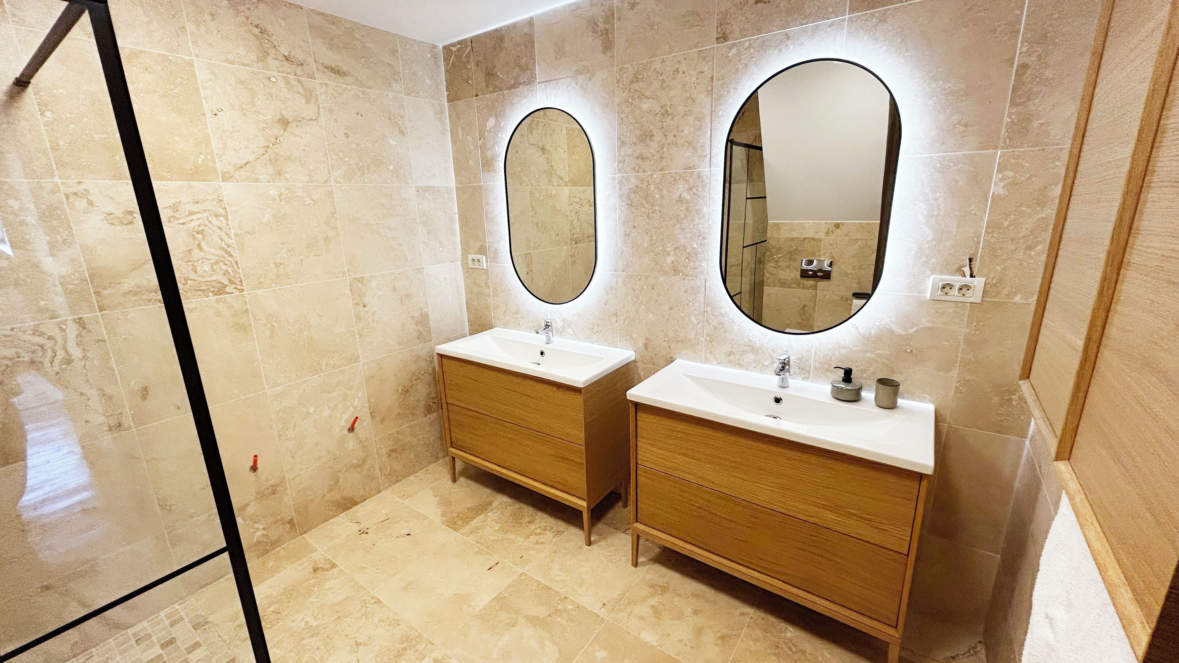Baño con dos lavamanos, armarios de madera y espejos grandes.