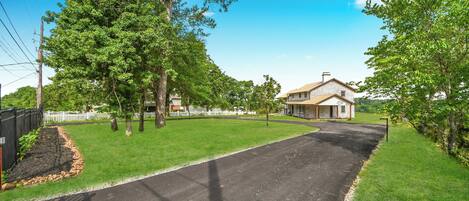 En bostadsgata med en asfalterad uppfart, ett hus med ett garage och en välskött gräsmatta.