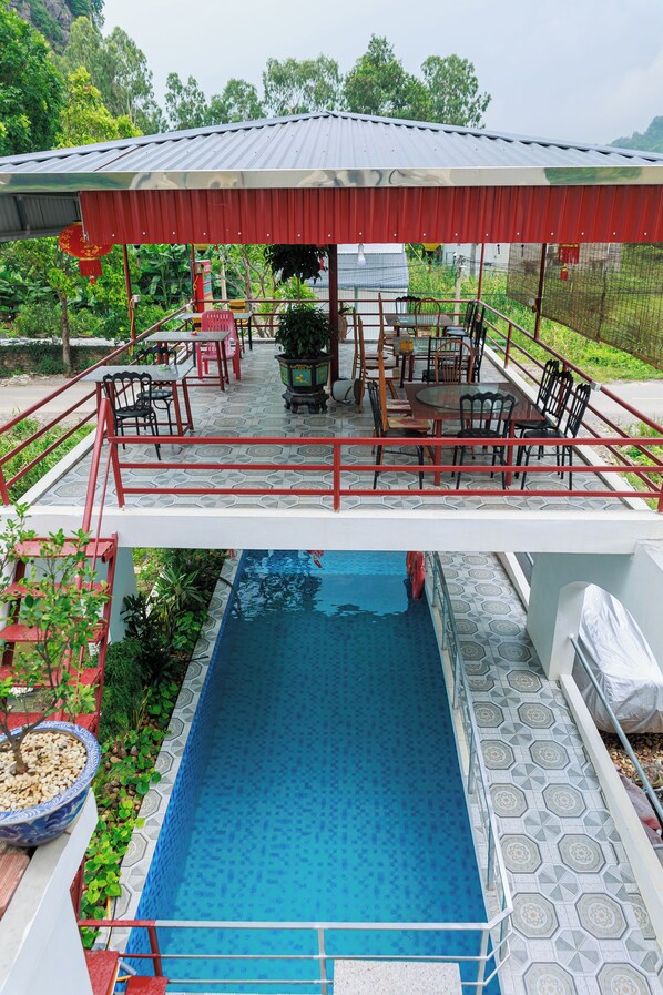 Zona de piscina con un área de descanso cubierta y una piscina.