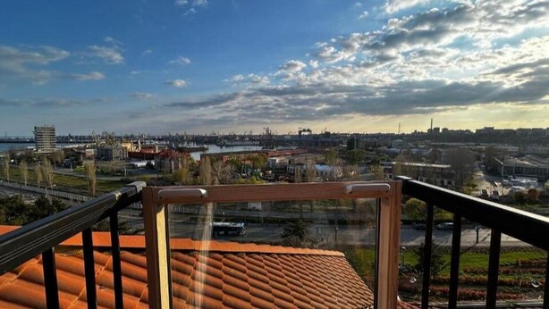 A balcony with a view of a cityscape, including buildings and a body of water. - The Admiral / Luxury Apartment in Constanta (Unknown)