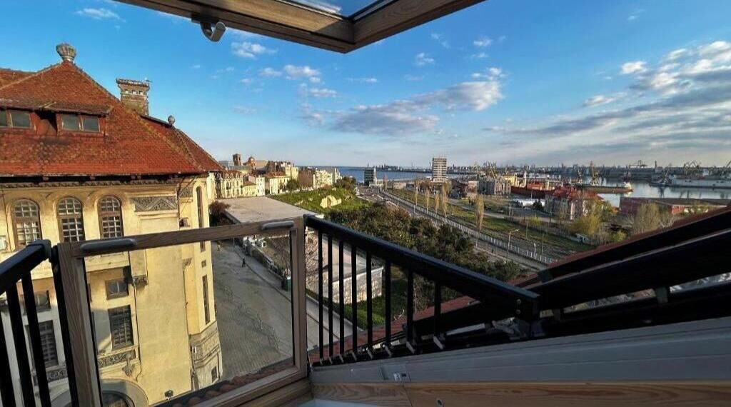 A balcony with a view of a cityscape, including buildings and a river.