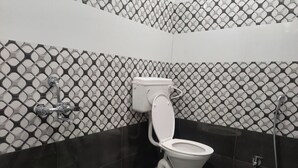 Un baño con inodoro, ducha y un cubo verde.