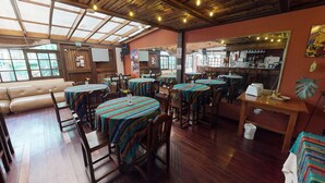 Ein Restaurant mit Holztischen und -stühlen, einer Bar und einem großen Spiegel an der Wand.