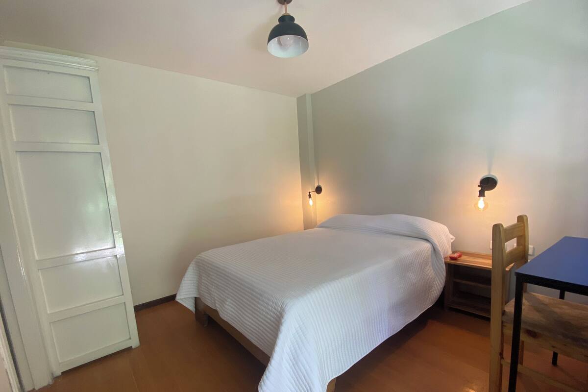A bedroom with a bed, bedside tables, a chair, and a door.