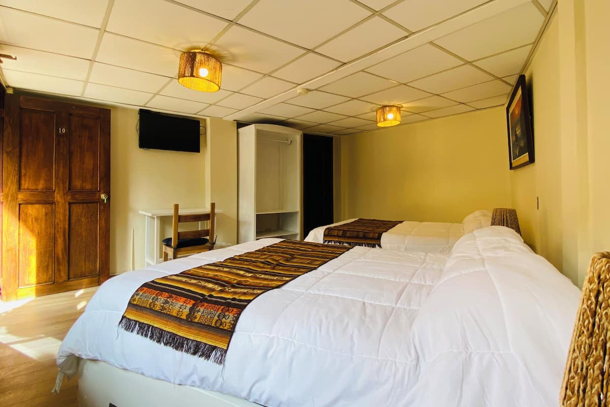 A hotel room with a large bed, a desk, and a wardrobe.