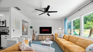 A modern living room with a sofa, a coffee table, and a TV displaying 'NETFLIX'. - 5BR~Huge Backyard~Minigolf~Heated Pool~Outdoor Projector~Gameroom~FIOS WiFi (Brandon)