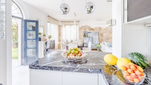 A modern kitchen with marble countertops, a fruit bowl, and a stone backsplash.