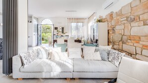A modern living room with a sofa, a stone wall, and a view of the outdoors.