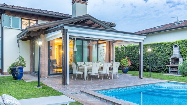 A covered outdoor patio with a pool, a dining area, and a barbecue grill.