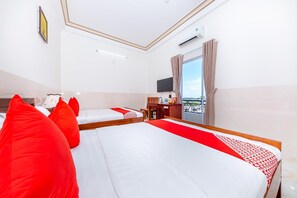 A hotel room with two beds, a desk, a chair, a television, and a window with a view. - Magnolia Hotel Cam Ranh (Bac Cam Ranh)