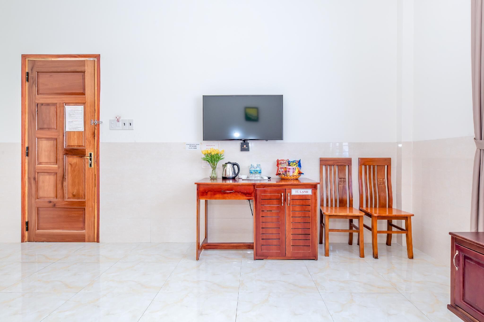 A room with a wooden desk, two chairs, a television, and a cabinet.