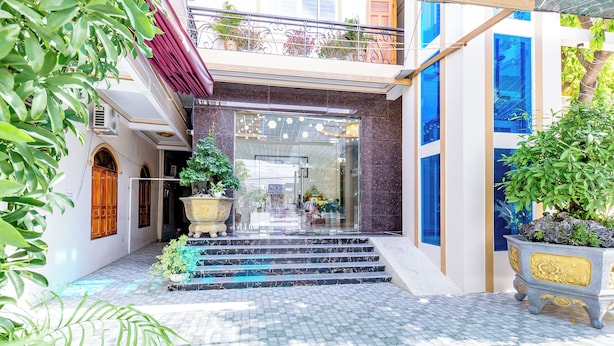 A hotel entrance with a marble staircase, a glass door, and potted plants.