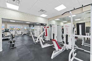 Uma academia com diversos aparelhos de exercício, espelhos e uma área de recepção.