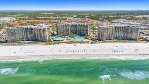 Um hotel à beira-mar com vários edifícios, uma praia de areia e vista desobstruída para o oceano.