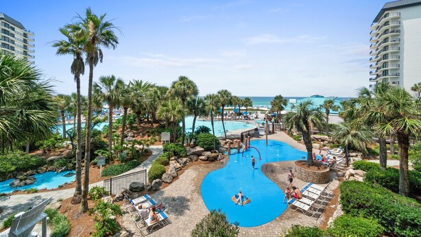 Ein Resort mit einem zentralen Pool, Palmen und Blick auf den Ozean.