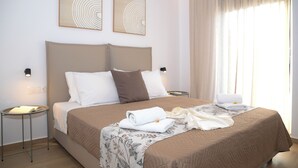 A neatly made bed with a beige bedspread, two pillows, and a folded towel. There are two wall-mounted light fixtures on either side of the bed.
