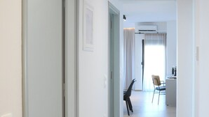 A hallway with a wooden floor leading to a dining area with chairs and a table.