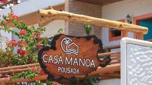 A wooden sign with the text "CASA MANOA POUSA DA" hanging from a wooden structure. - CASA MANOA POUSADA (Maragogi)