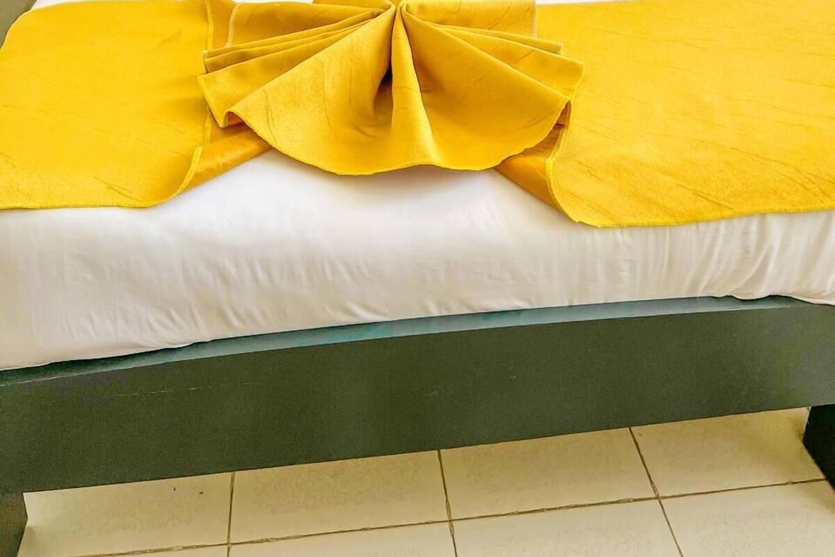 A bed with white bedding, a blue headboard, and yellow accents.