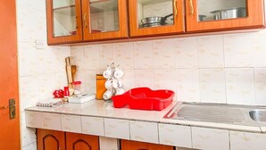 A kitchen with wooden cabinets, a sink, and a red dish rack. - Lux Suites Cabre Apartments (Nakuru)
