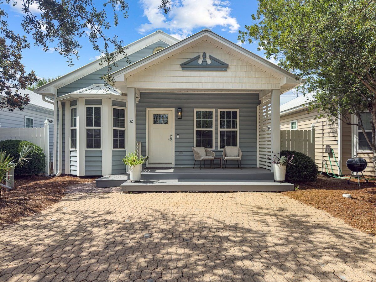 A two-story house with a covered front porch, a mailbox, and a number 32 sign.