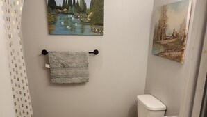 Une salle de bain équipée de toilettes, d’un lavabo et de deux tableaux accrochés au mur.