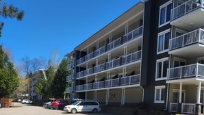 Un immeuble à plusieurs étages doté de balcons, d’un espace de stationnement et d’arbres.