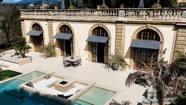 Una villa lujosa con piscina, mobiliario exterior y ventanas arqueadas.