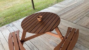 A wooden picnic table with benches on a wooden deck.